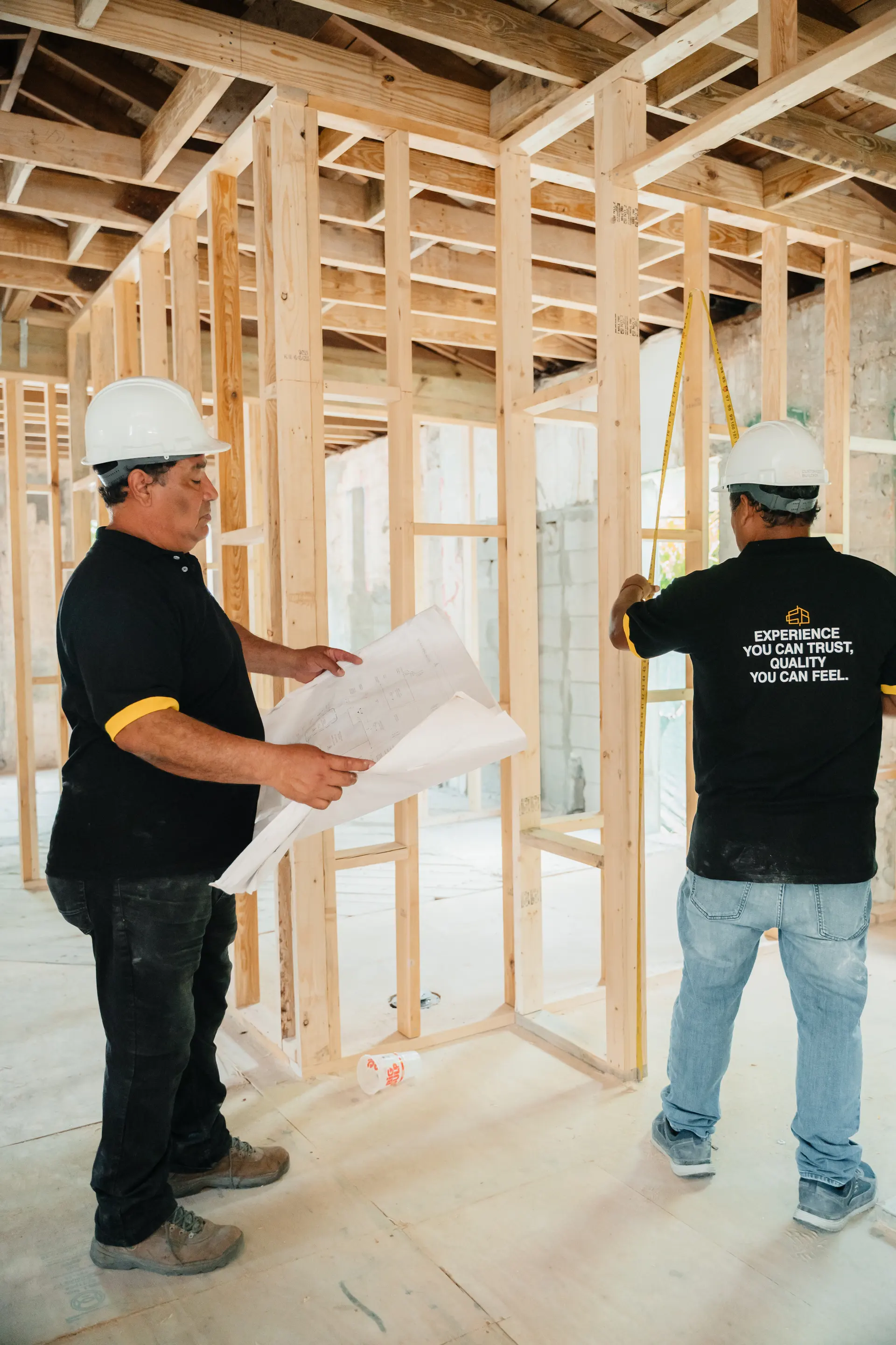 Team member checking blueprints within a newly framed structure