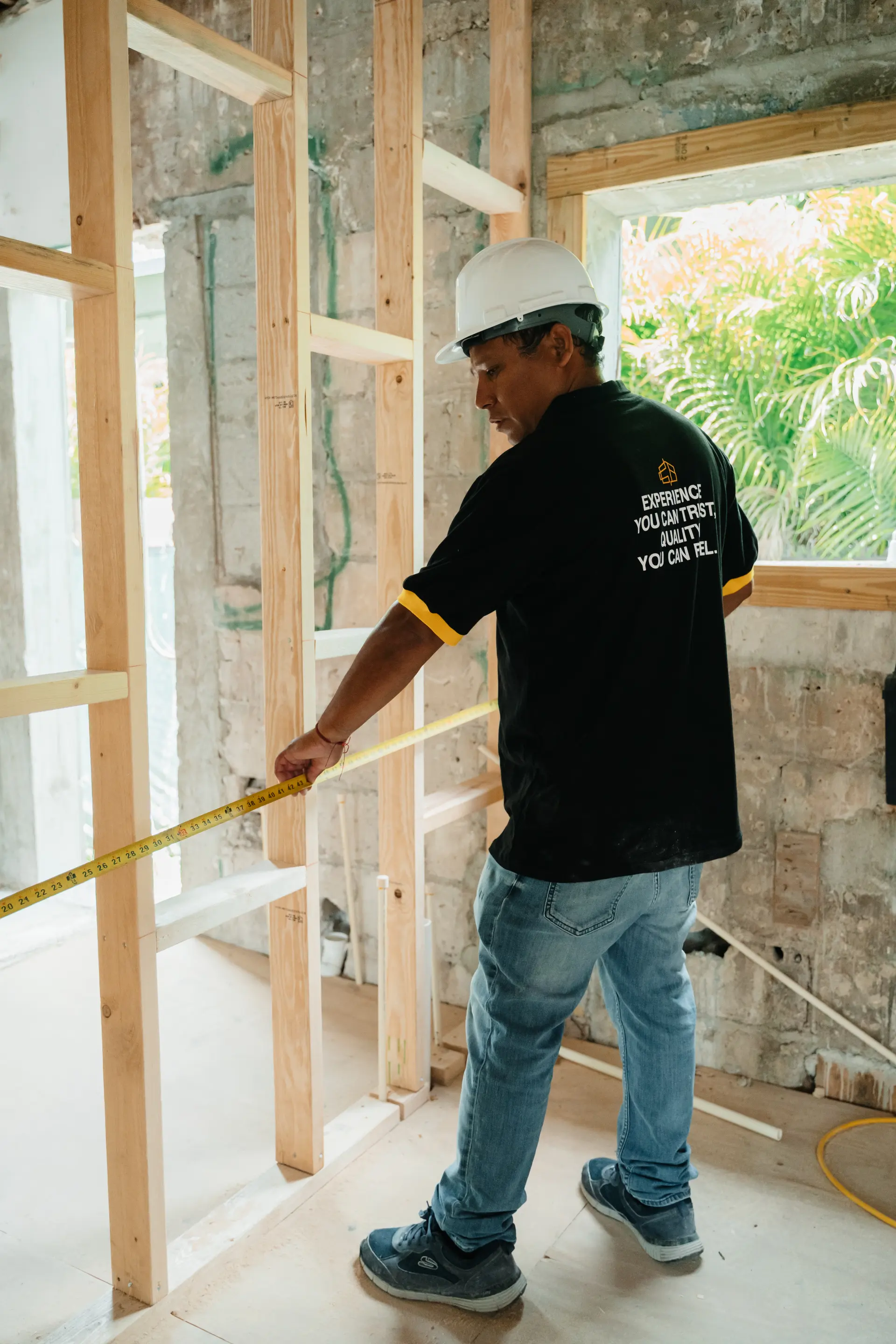 Customized Builders craftsman measuring framing on an active construction site