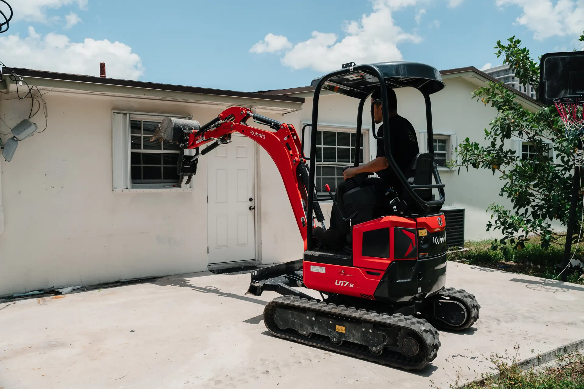 Compact excavator performing structural demolition on a renovation project